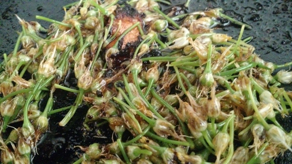 scallion blossoms cooking in skillet